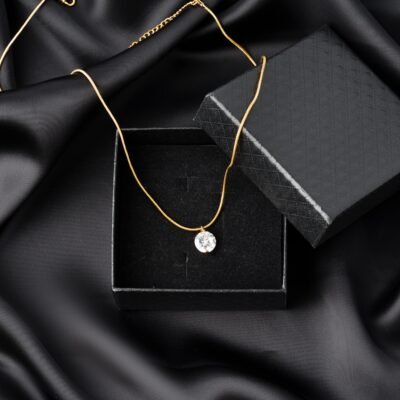 Golden necklace on silk texrtile background close up